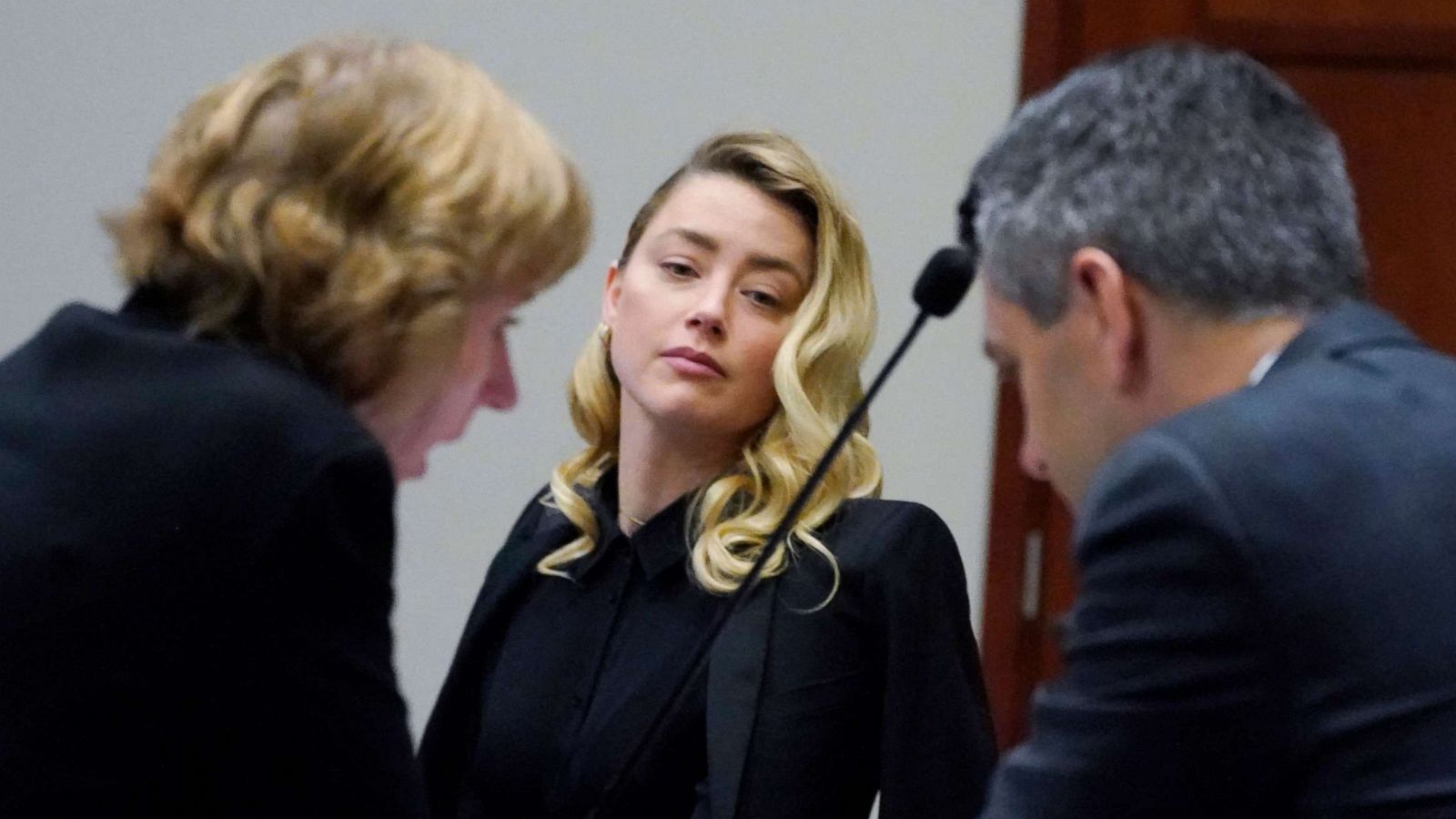 PHOTO: Actress Amber Heard looks over at her attorneys Elaine Bredehoft, left and Ben Rottenborn, right, during a break in the courtroom at the Fairfax County Circuit Court in Fairfax, Virginia, April 18, 2022.