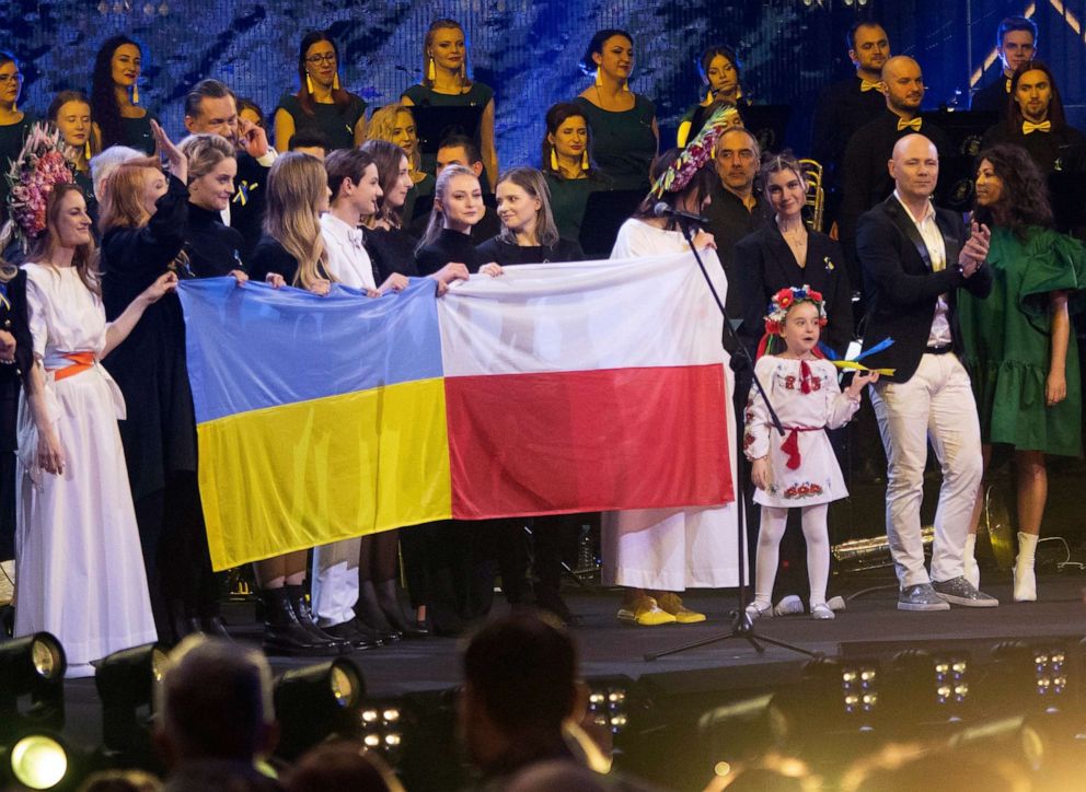 PHOTO: Seven-year-old Amellia Anisovych, a refugee from Ukraine, stands to the right of the Ukrainian and Polish flags in the finale of a fund-raising concert in Lodz, Poland, March 20, 2022.