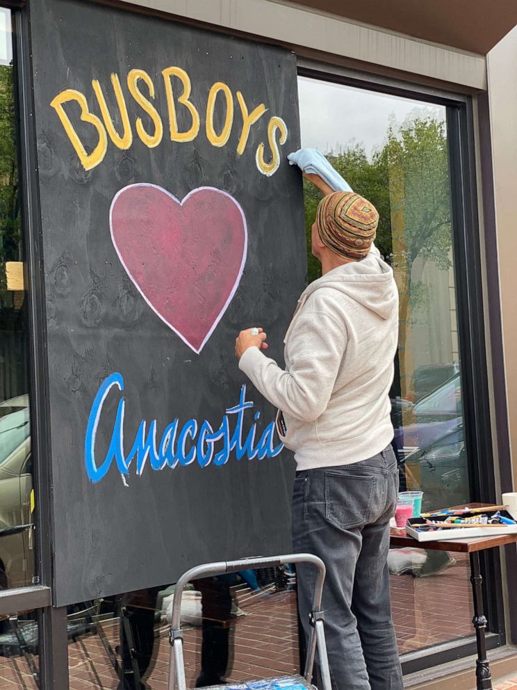 PHOTO: Busboys and Poets owner Andy Shallal paints the Busboys and Poets store front at the Anacostia location in Washington, D.C.
