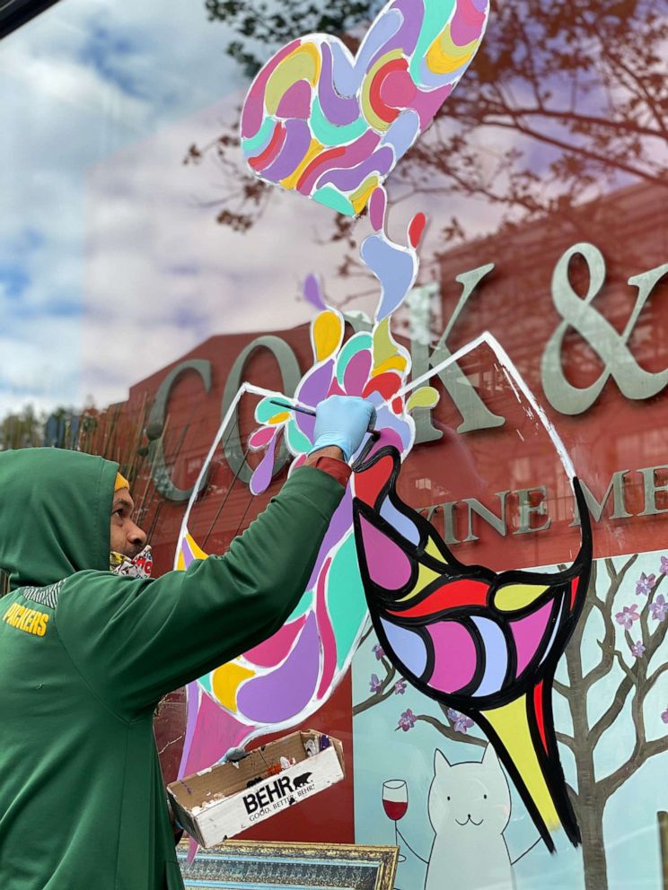 PHOTO: Artist Luther Wright paints the store front of Washington, D.C. restaurant Cork & Fork.