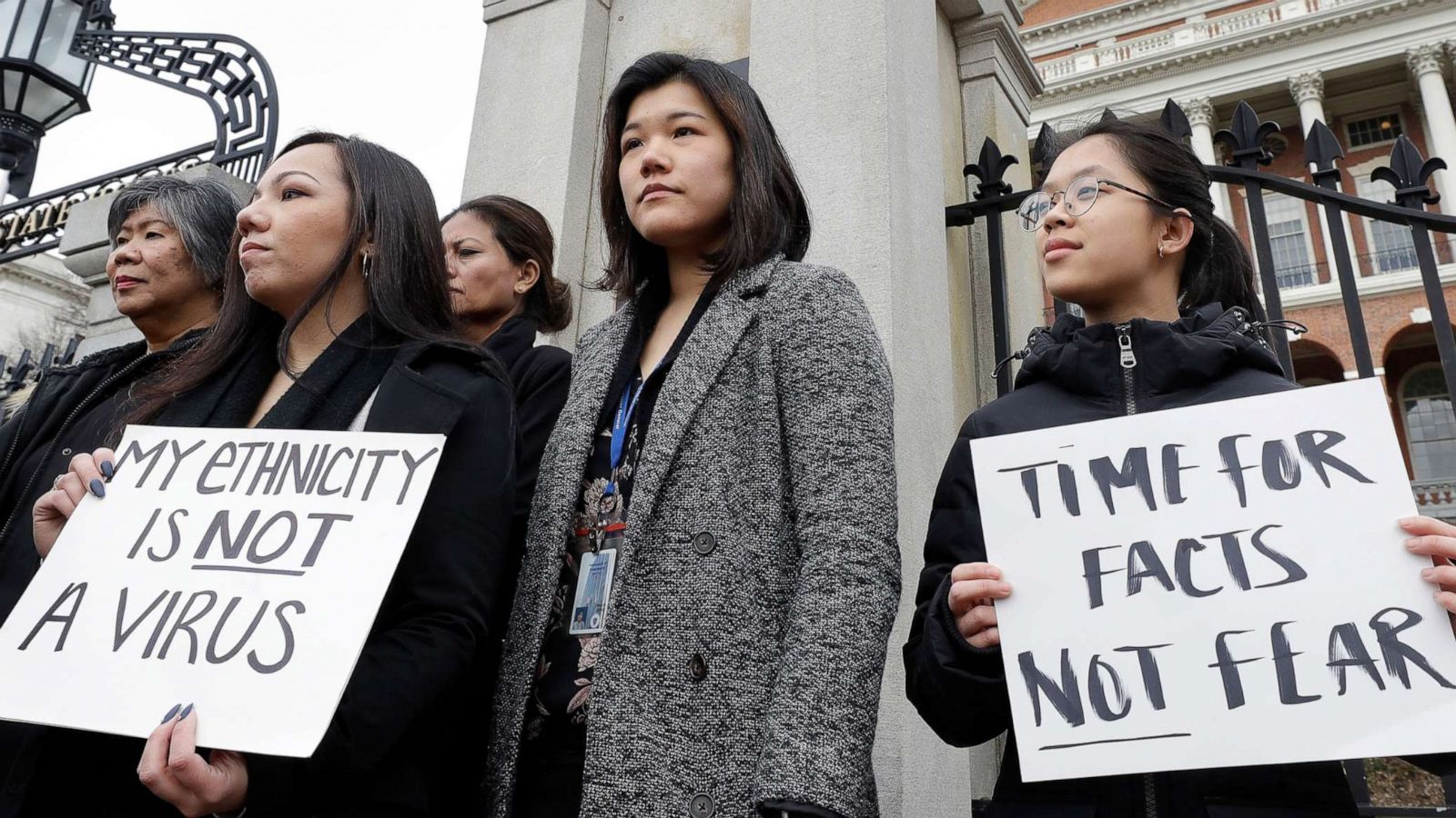 PHOTO: Women from the Massachusetts Asian American Commission stand together during a protest, March 12, 2020, on the steps of the Statehouse in Boston.