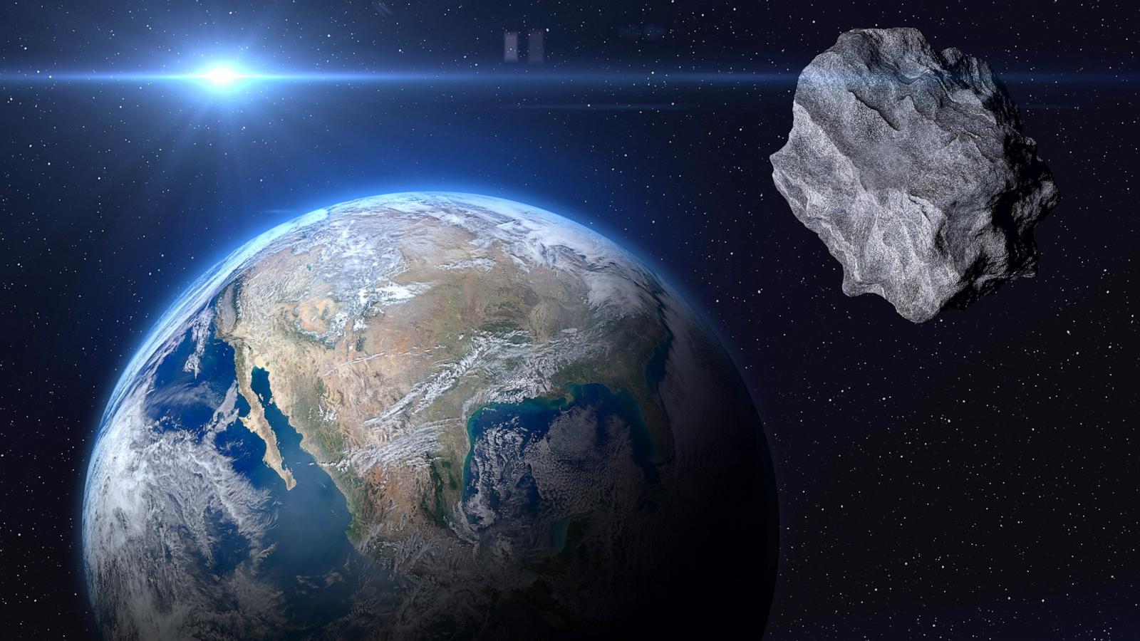 PHOTO: planet Earth and a big asteroid in space.