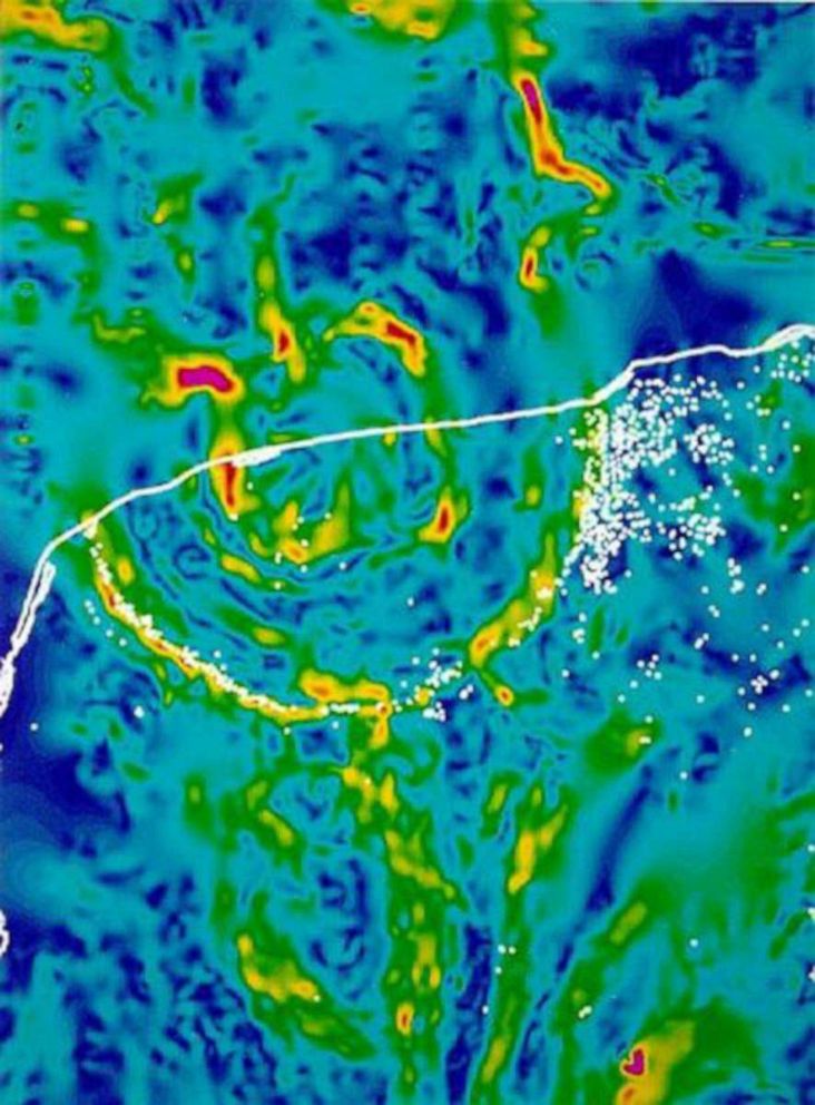 PHOTO: A gravity map showing the ringed outline of the impact crater. The white line represents the edge of the Yucatan Peninsula. The white dots are cenotes.