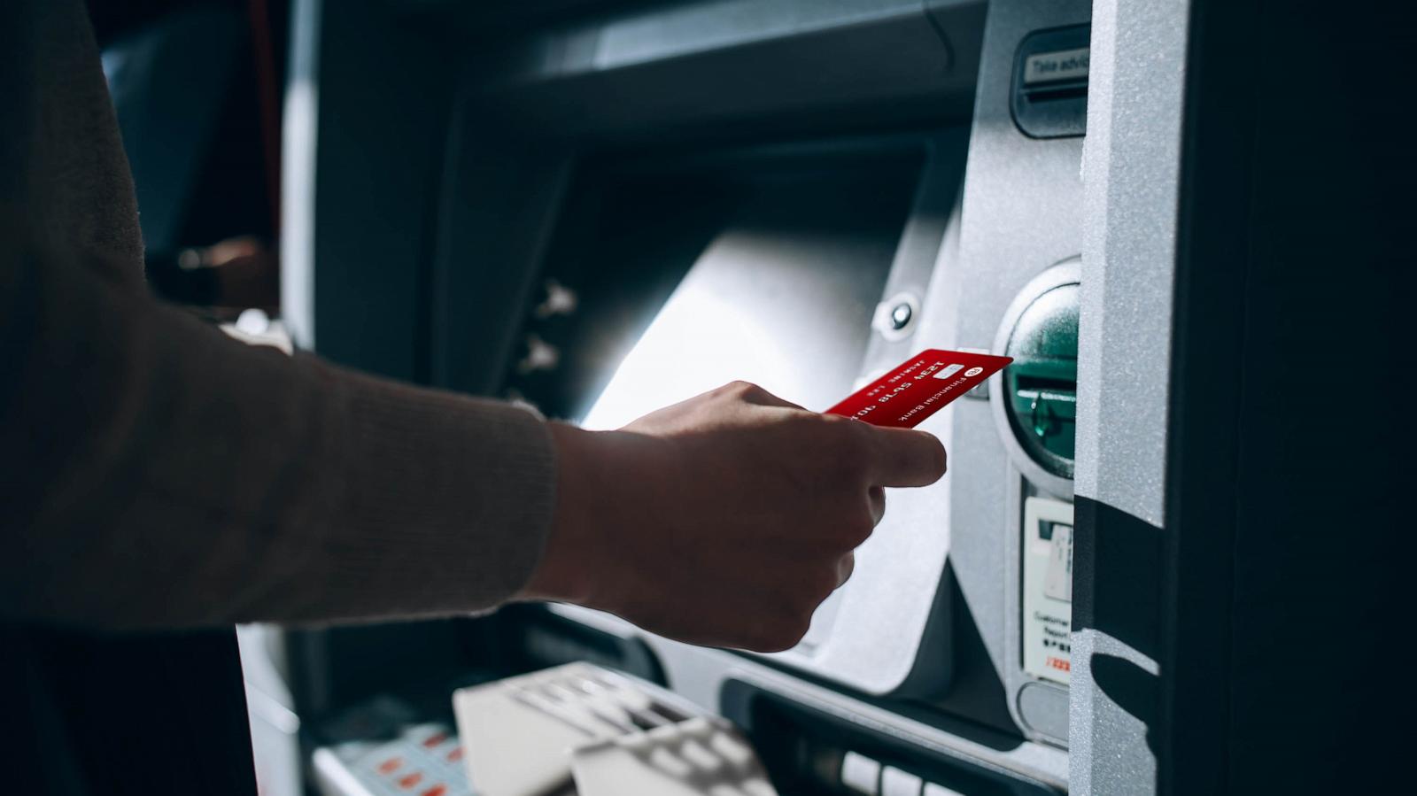 PHOTO: Close up of young woman inserting her bank card into automatic cash machine in the city.