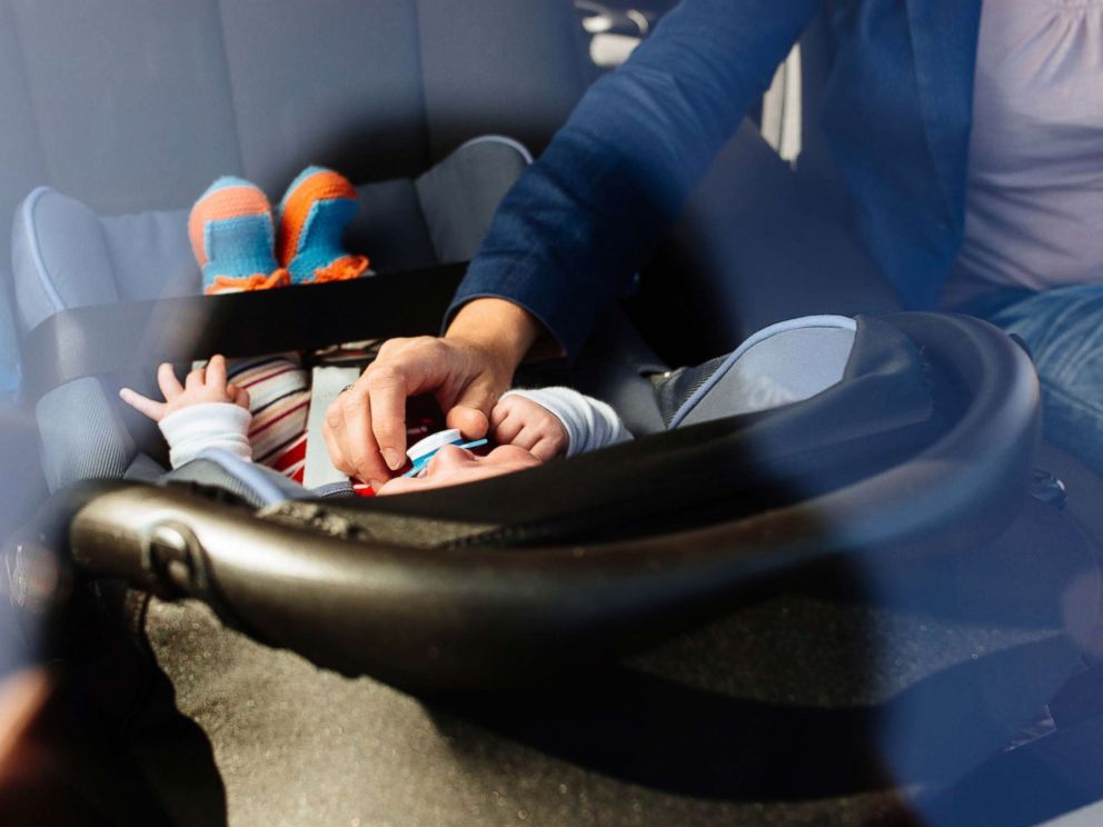 PHOTO: In this undated stock photo, a mother puts her baby in a rear facing car set.