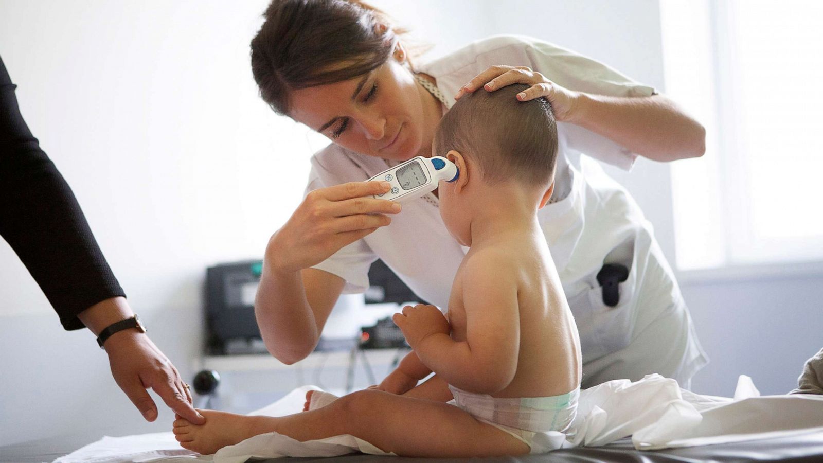 PHOTO: Pediatric nurse takes a young child's temperature at a medical facility.