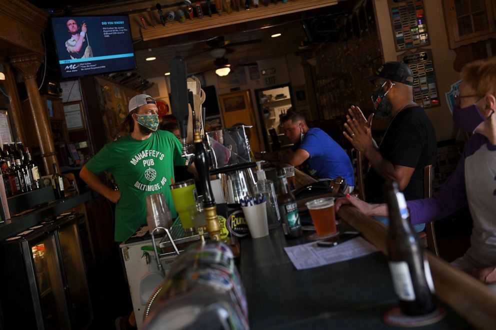 PHOTO: In this July 23, 2020, file photo, Dennis Kistner, owner of Mahaffreys Pub chats with customers from behind the bar in Baltimore, Md.