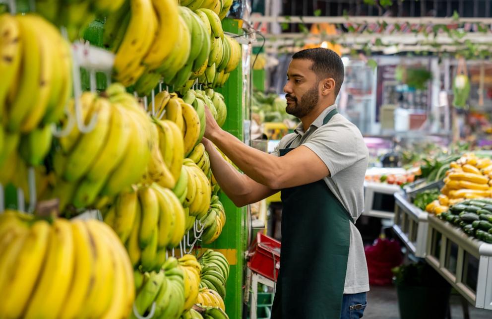 PHOTO: An employee working at a supermarket organizing some bananas