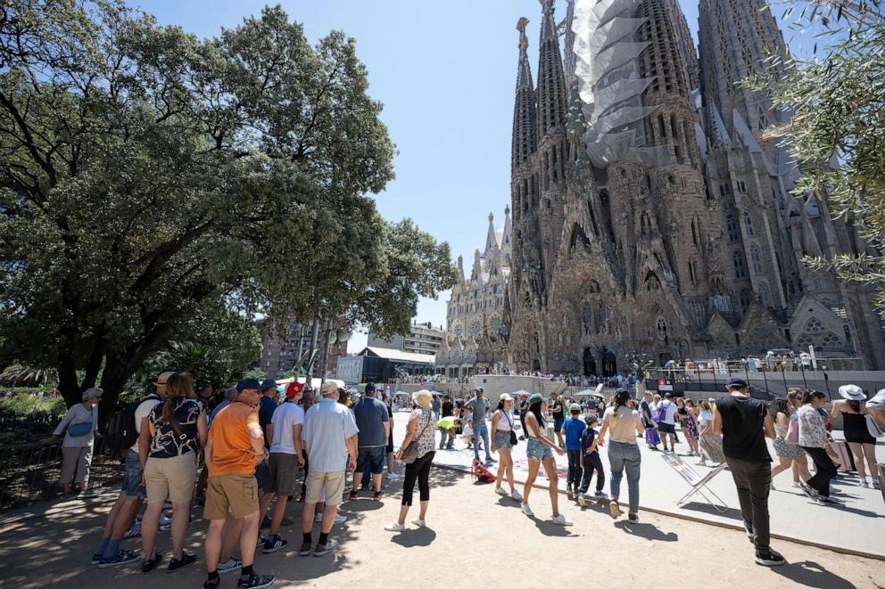 PHOTO: Tourists walk past the Sagrada Familia basilica in Barcelona on July 5, 2024. 