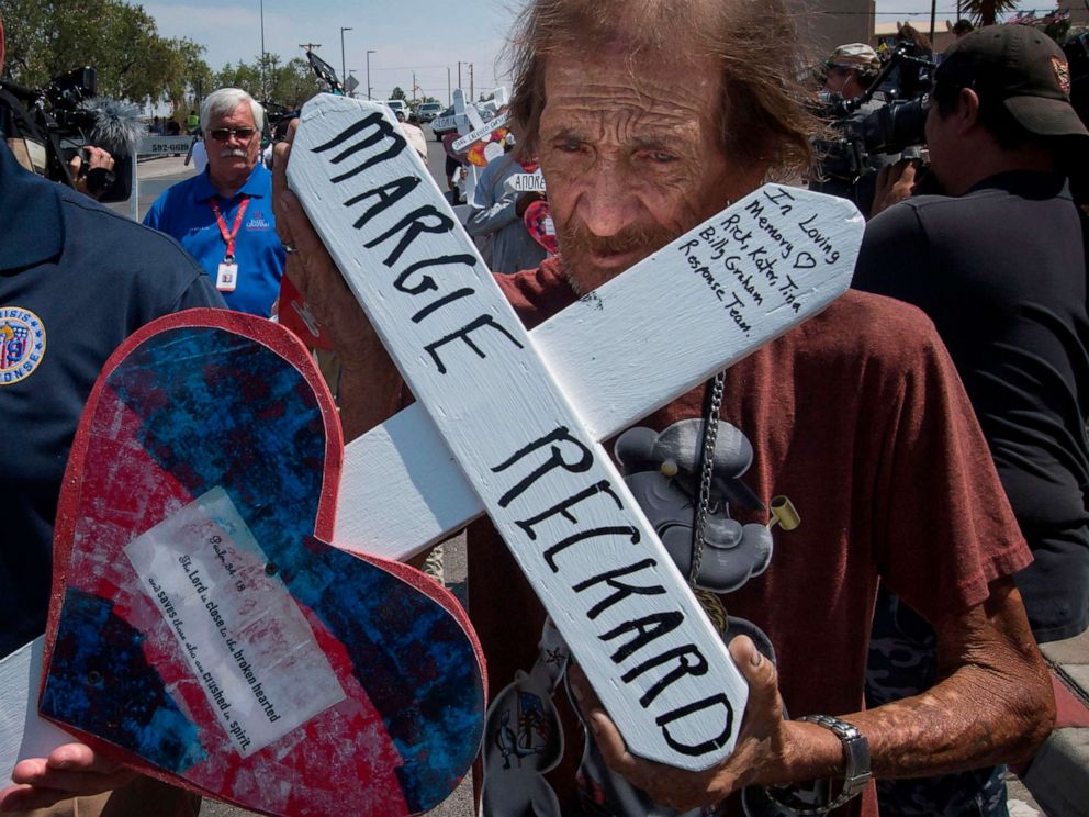 PHOTO: Antonio Basco holds the cross of his common-law wife, Margie Reckard, who died in the Walmart shooting as he walks to a makeshift memorial in El Paso, Texas, Aug. 5, 2019.