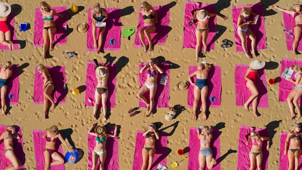 PHOTO: Swimsuit wearing sunbathers lay on beach towels in an undated stock image.