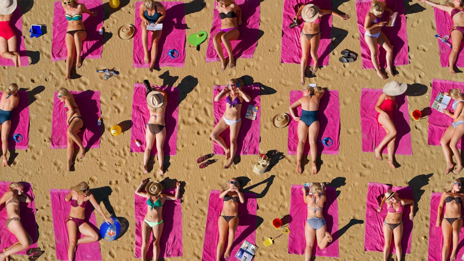 PHOTO: Swimsuit wearing sunbathers lay on beach towels in an undated stock image.