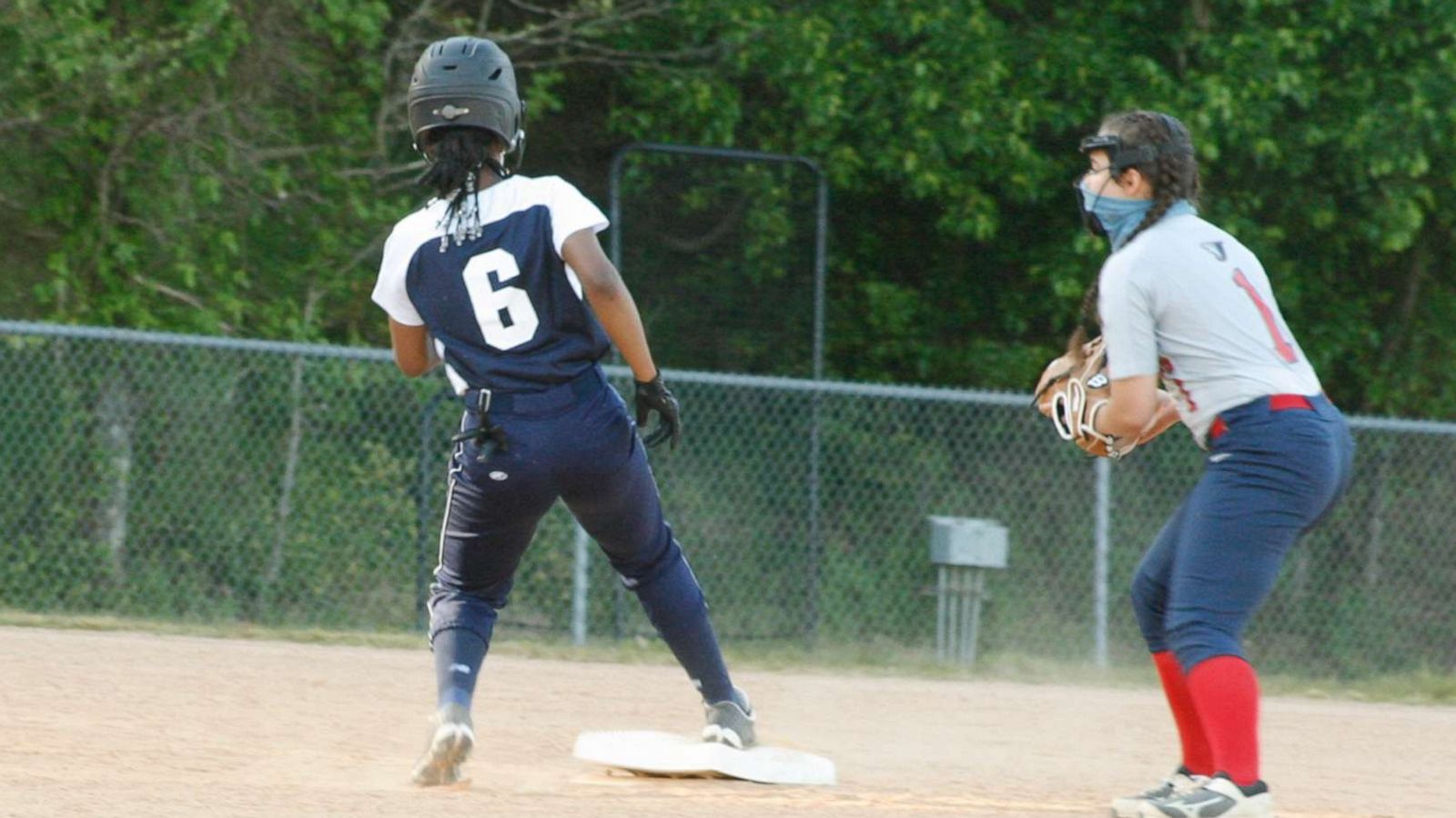 PHOTO: Hillside High School student, Nicole Pyles (seen on the left), plays in a softball game on April 19 with her beaded knotless braids tied in a ponytail in Durham, N.C.