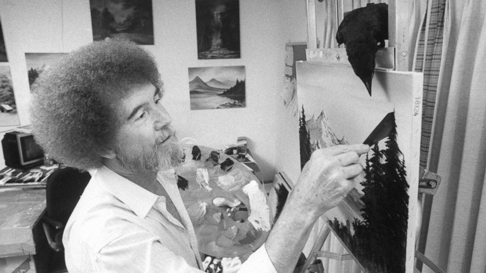 PHOTO: TV painting instructor/artist Bob Ross paints one of his landscapes as his pet crow watches closely from its perch on top of easel in studio at home on July 16, 1991.