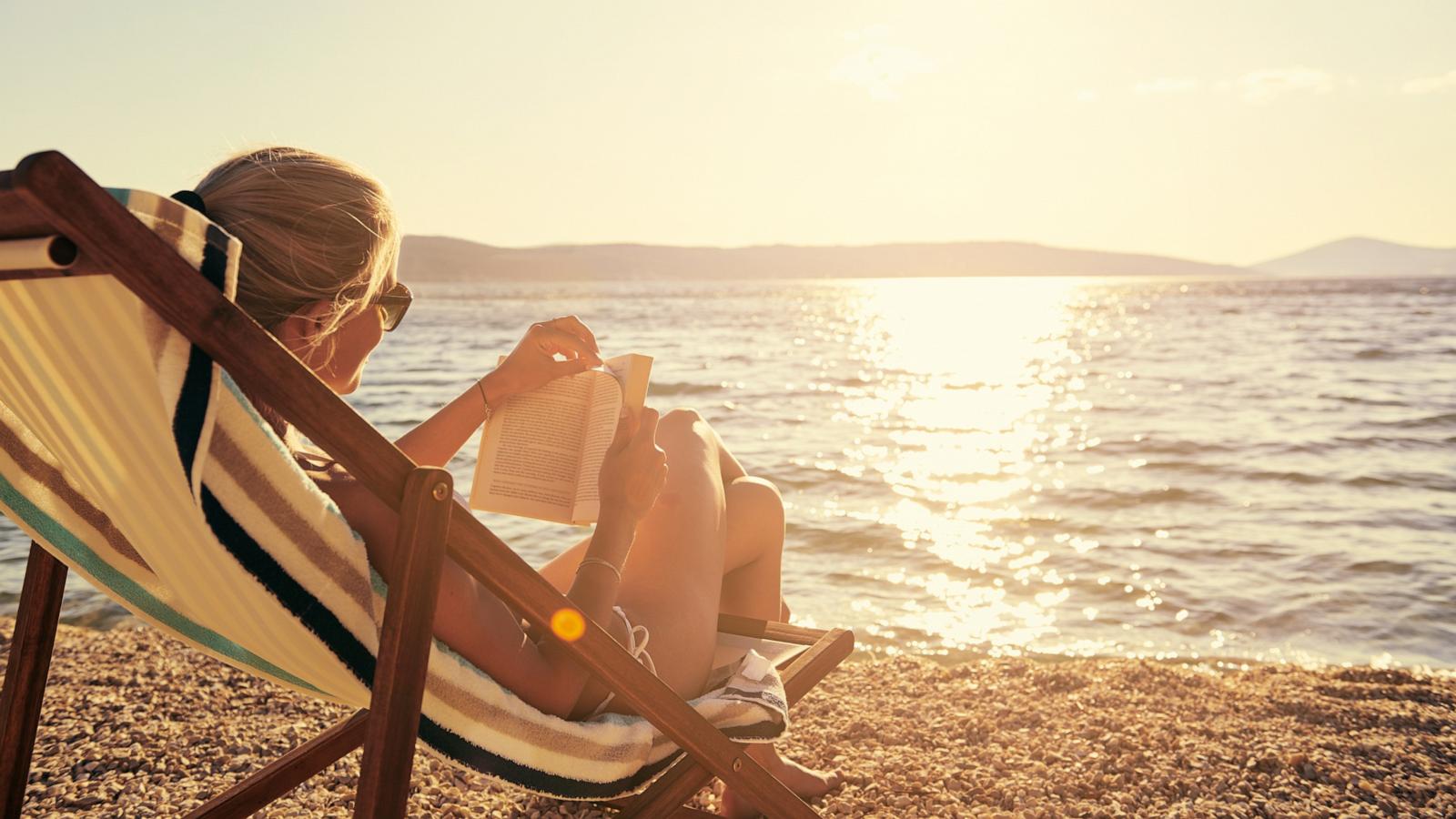 PHOTO: A woman reads a book while sitting at the beach.