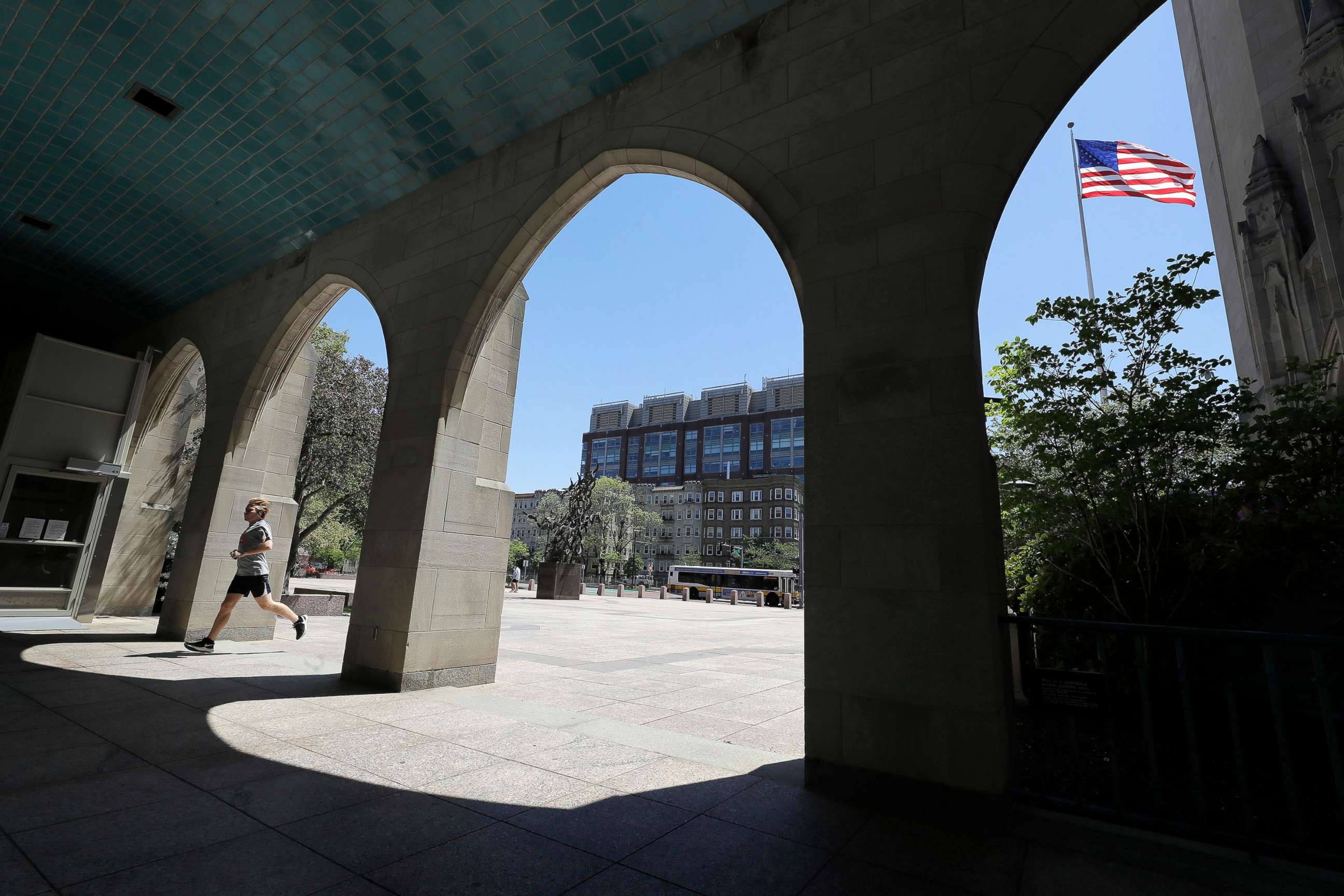 PHOTO: A runner passes through an arch on the campus of Boston University, in Boston, May 20, 2020.