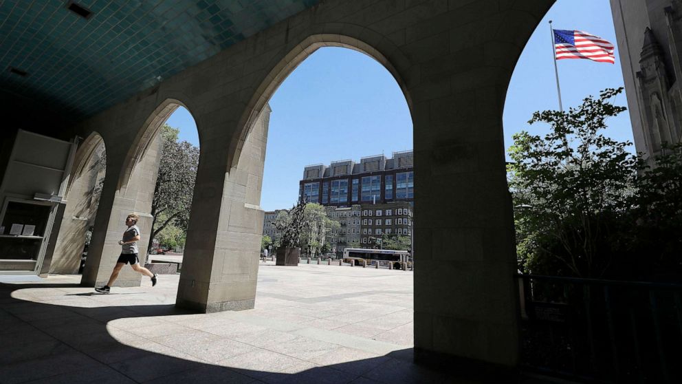 PHOTO: A runner passes through an arch on the campus of Boston University, in Boston, May 20, 2020.