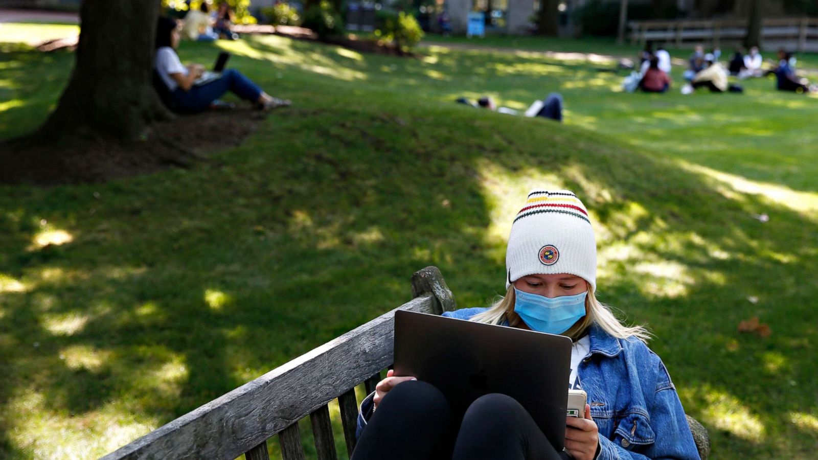 PHOTO:A student wears a mask as she works on her laptop outside on the BU Beach at Boston University in Boston on Sept. 23, 2020.