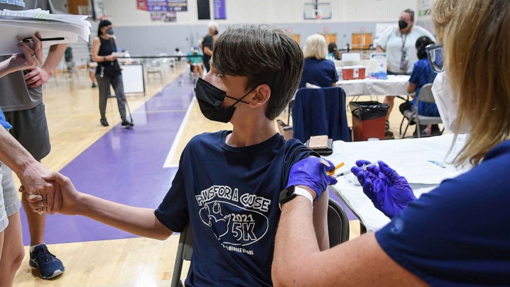 PHOTO: A 12 year old boy holds his mother's hand while a nurse gives him a shot of the Pfizer COVID-19 vaccine at a vaccination clinic at Winter Springs High School, on Sept. 11, 2021, in Winter Springs, Fla.