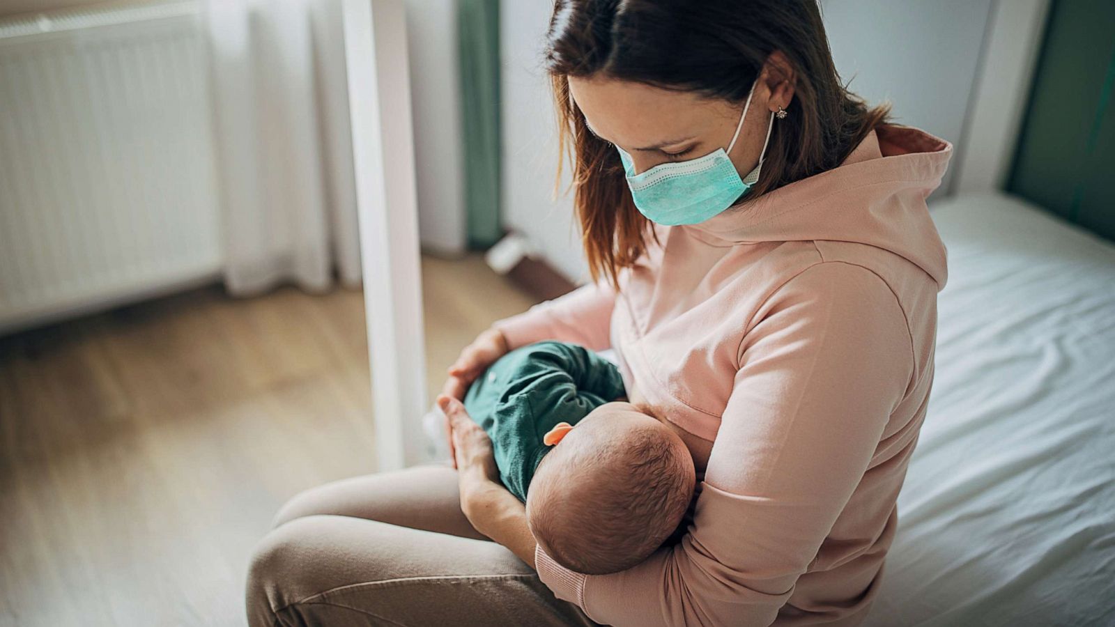 PHOTO: In this undated file photo, a mother wears a mask while breastfeeding her baby at home.