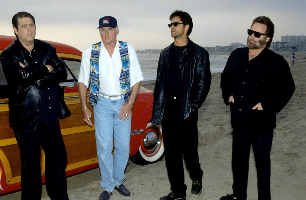 PHOTO: In this 1995 file photo, musicians Brian Wilson, Mike Love, actor John Stamos and musician Carl Wilson, of the American rock band The Beach Boys, talk at a beach in Los Angeles.