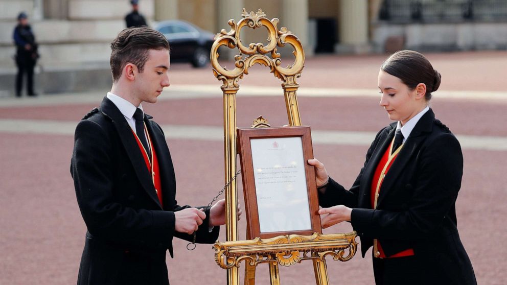 Members of staff set up an official notice on an easel at the gates of Buckingham Palace in London on May 6, 2019 announcing the birth of a son to Britain's Prince Harry, Duke of Sussex and Meghan, Duchess of Sussex.