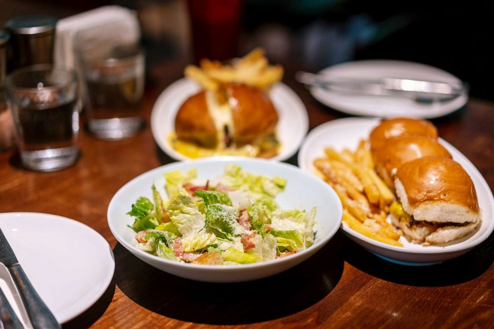 PHOTO: A Caesar salad bowl and french fries and a sandwich plate in a restaurant.