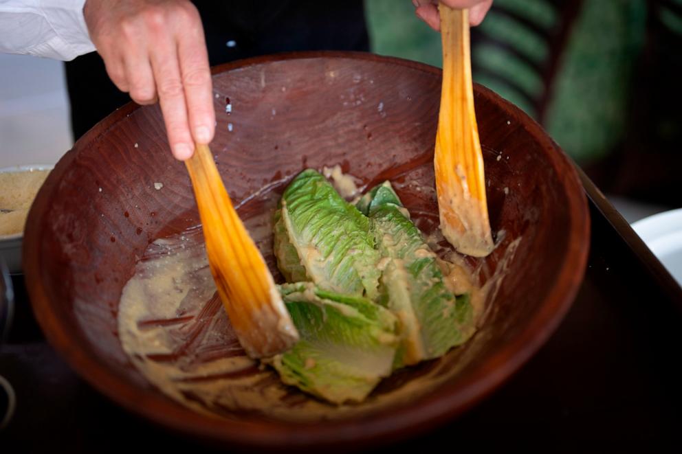 PHOTO: Salad Master Efrain Montoya mixes Romaine leaves with other ingredients as he prepares a Caesar salad at Ceasar's restaurant, June 27, 2024, in Tijuana, Mexico.