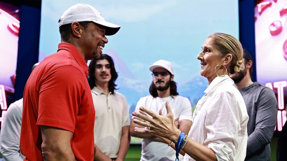 PHOTO: Tiger Woods of Jupiter Links Golf Club talks with singer Celine Dion after their TGL golf match against the Atlanta Drive GC, Mar. 4, 2025, in Palm Beach Gardens, Fla.