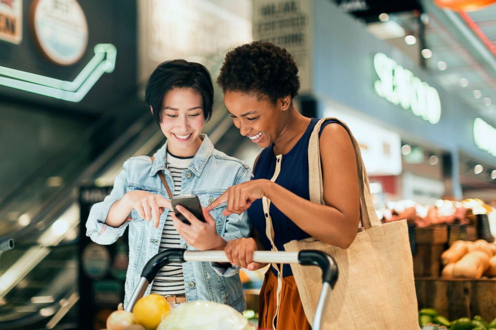 PHOTO: Two women scroll on a cellphone in this stock photo.