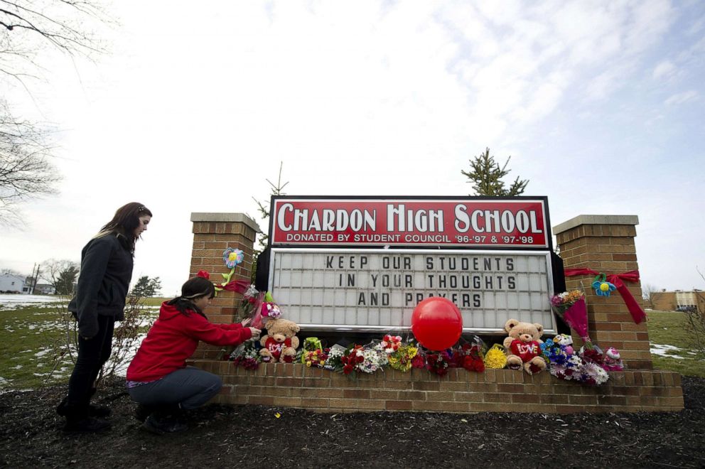 PHOTO: Maria Cochran and Andressa Green of Chardon place flowers on the sign outside Chardon High School in Chardon, Ohio, Feb. 28, 2012.