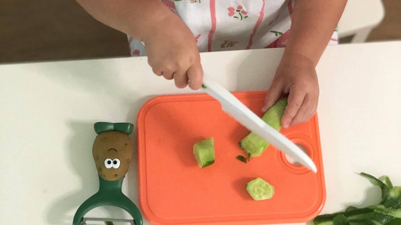 PHOTO: Charlotte chops a cucumber with the toddler kitchen knife.