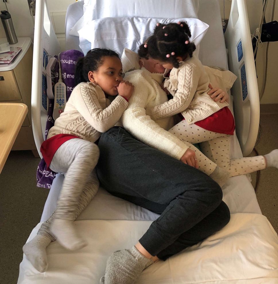 PHOTO: Charlotte Ngarukiye, of New Hampshire, is comforted by her two daughters while undergoing treatment for colorectal cancer.