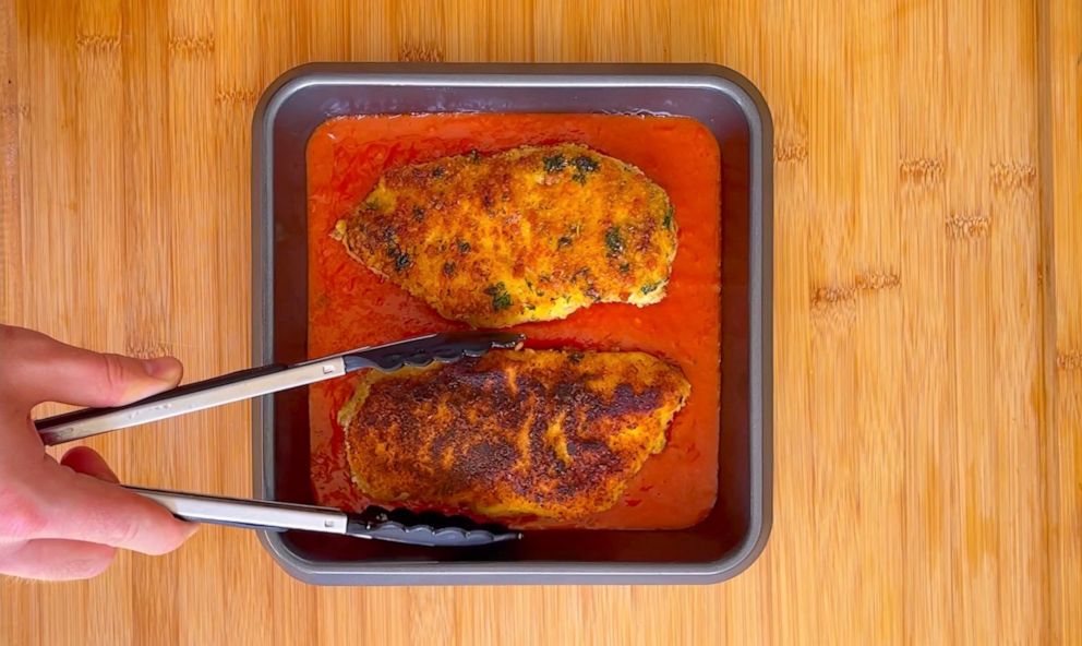 PHOTO: Chicken is placed in sauce before baking in the oven.