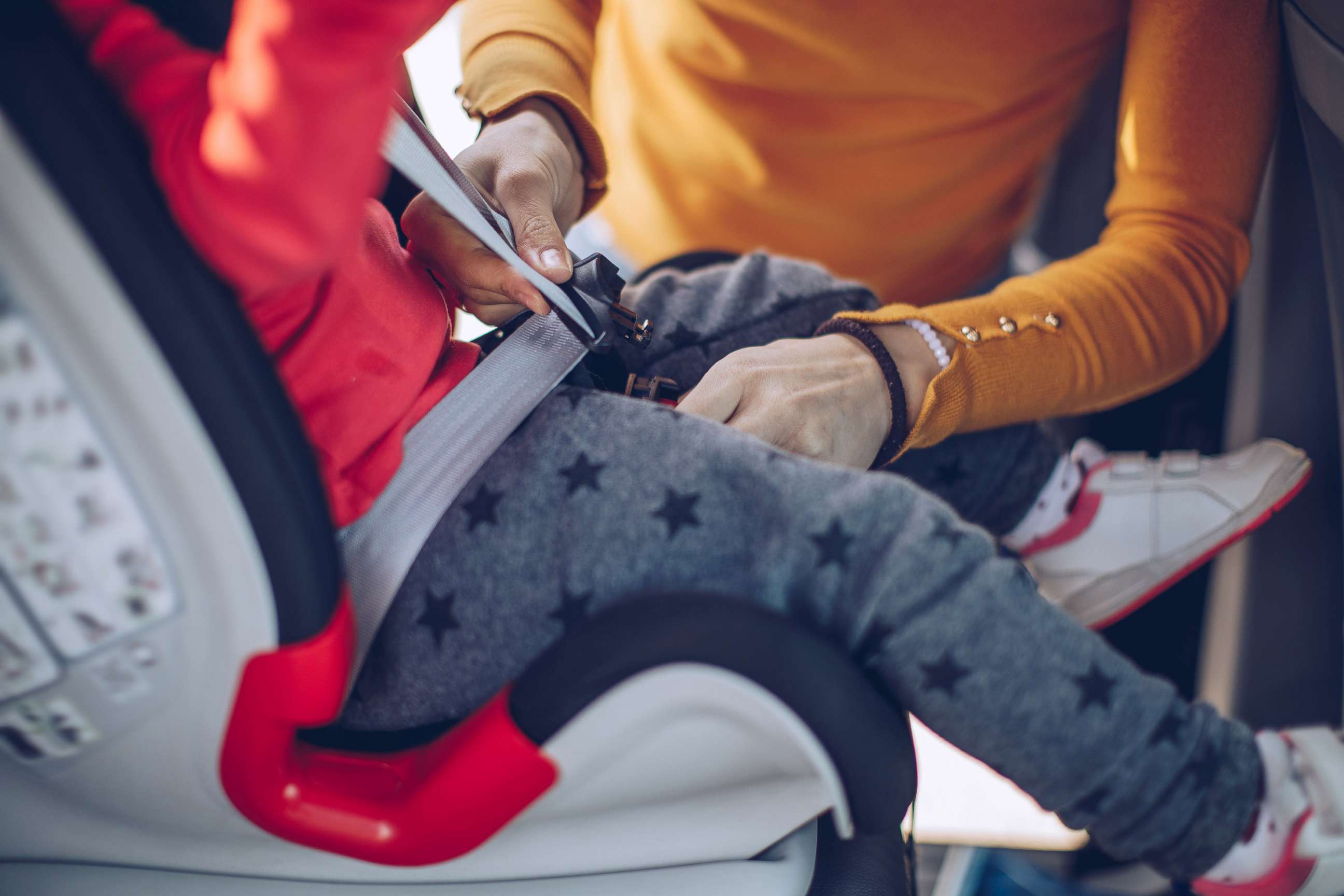 PHOTO: A woman buckles a child into a car safety seat.