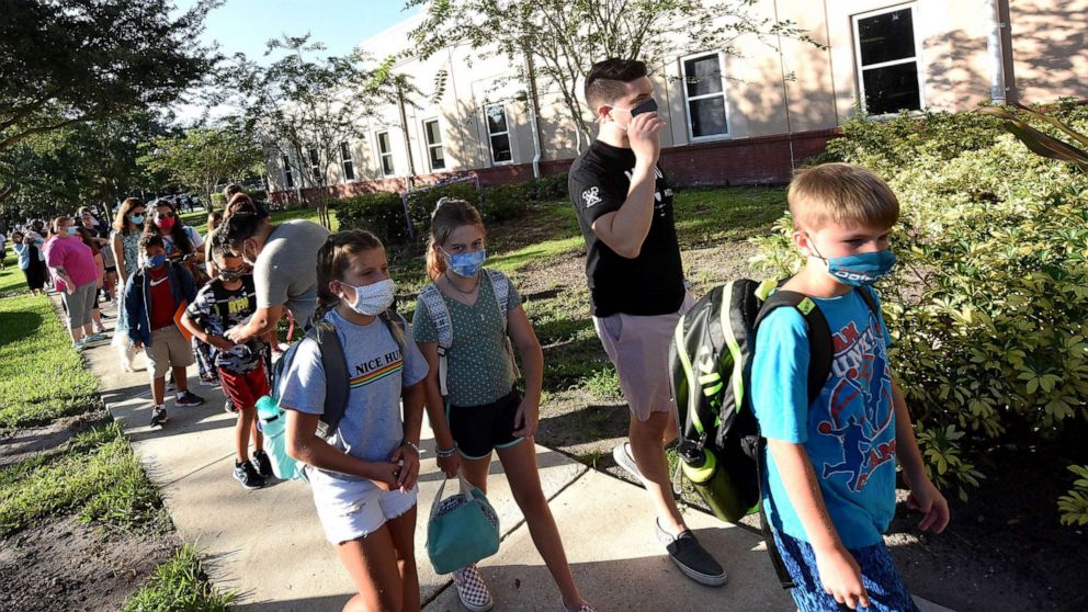 PHOTO: Students wearing face masks arrive with their parents on the first day of classes for the 2021-22 school year at Baldwin Park Elementary School, Orlando, FL.