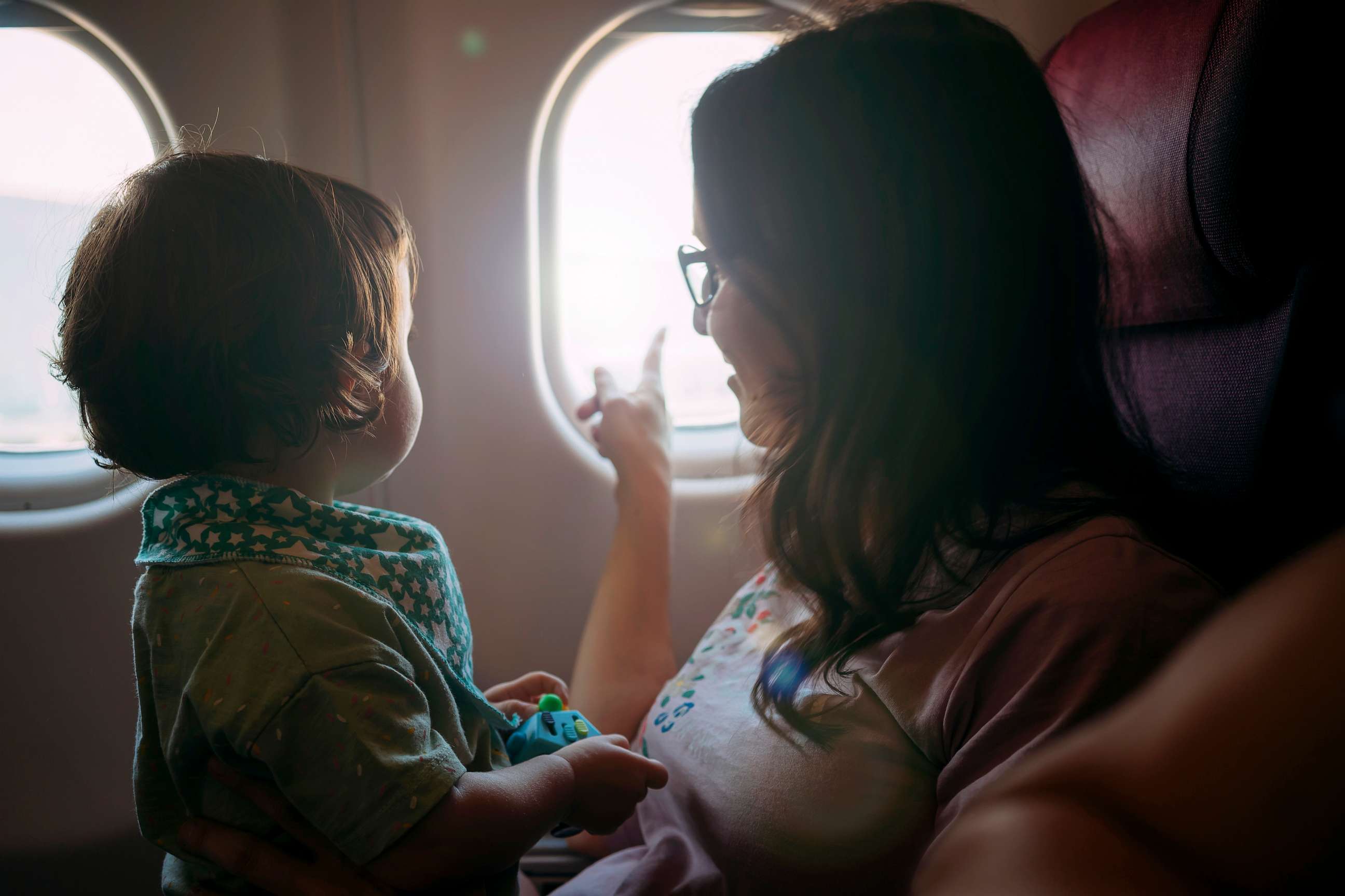 PHOTO: Stock photo of child on a parent's lap in a plane.