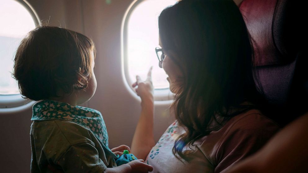 PHOTO: Stock photo of child on a parent's lap in a plane.