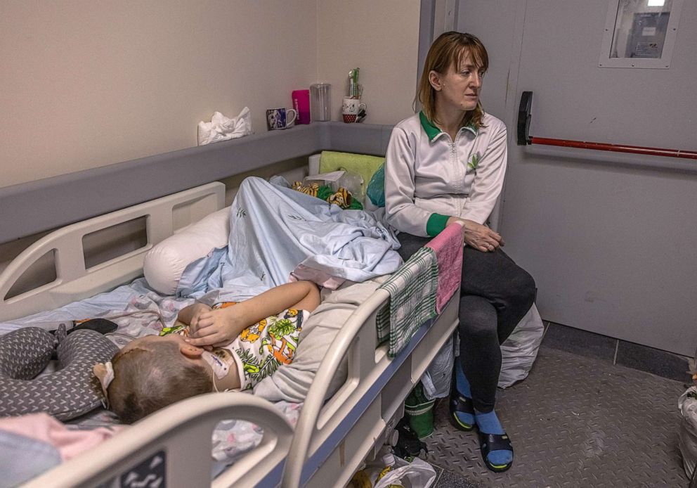 PHOTO: A woman sits next to a child the basement of the children's hospital in Kyiv, Ukraine, March 1, 2022.