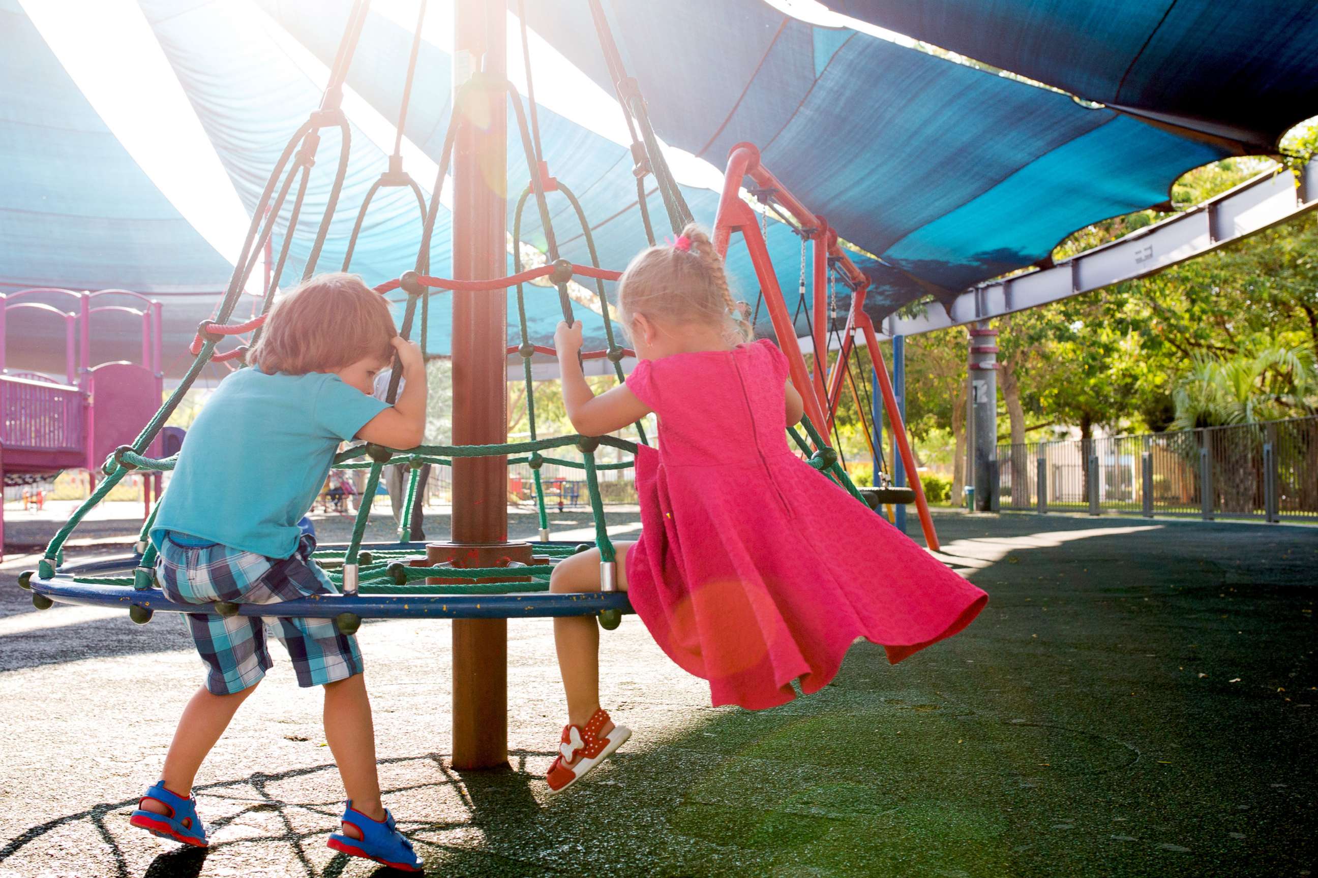 PHOTO: Rear view of little girl and boy having fun at outdoors playground.