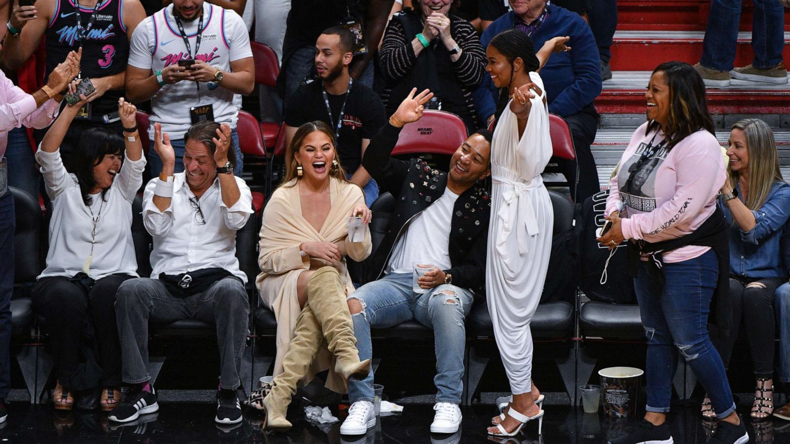 PHOTO:Chrissy Teigen and John Legend and Gabrielle Union react to the crowd after Dwyane Wade of the Miami Heat made a three point shot, April 9, 2019.