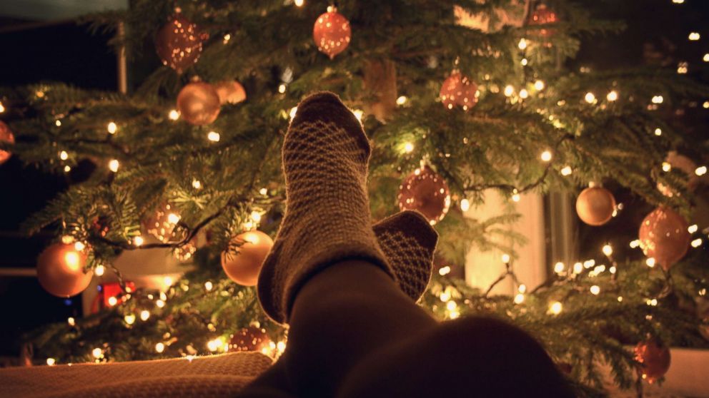 A person rests near a Christmas tree in an undated stock photo.