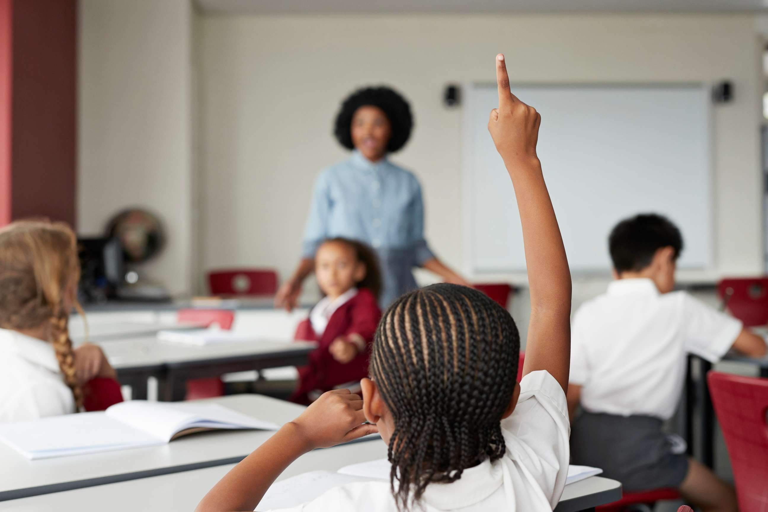 PHOTO: A child raises their hand during class in this stock photo. 