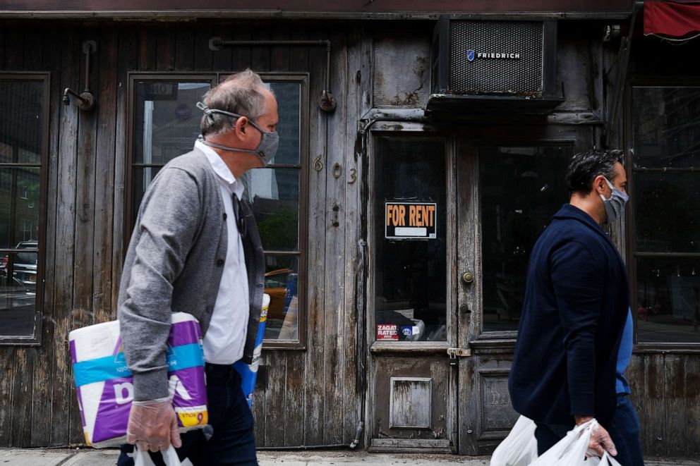 PHOTO: People walk by a closed restaurant in New York, May 18, 2020.