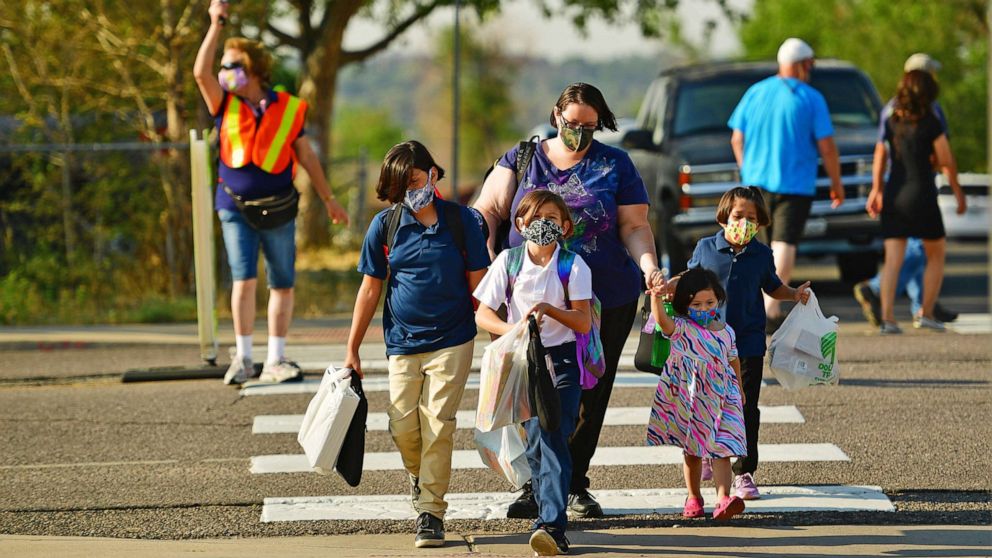 PHOTO: Students wearing masks walk to the main entrance of Hodgkins Leadership Academy on first day of school in Westminster, Colo., Aug. 20, 2020.