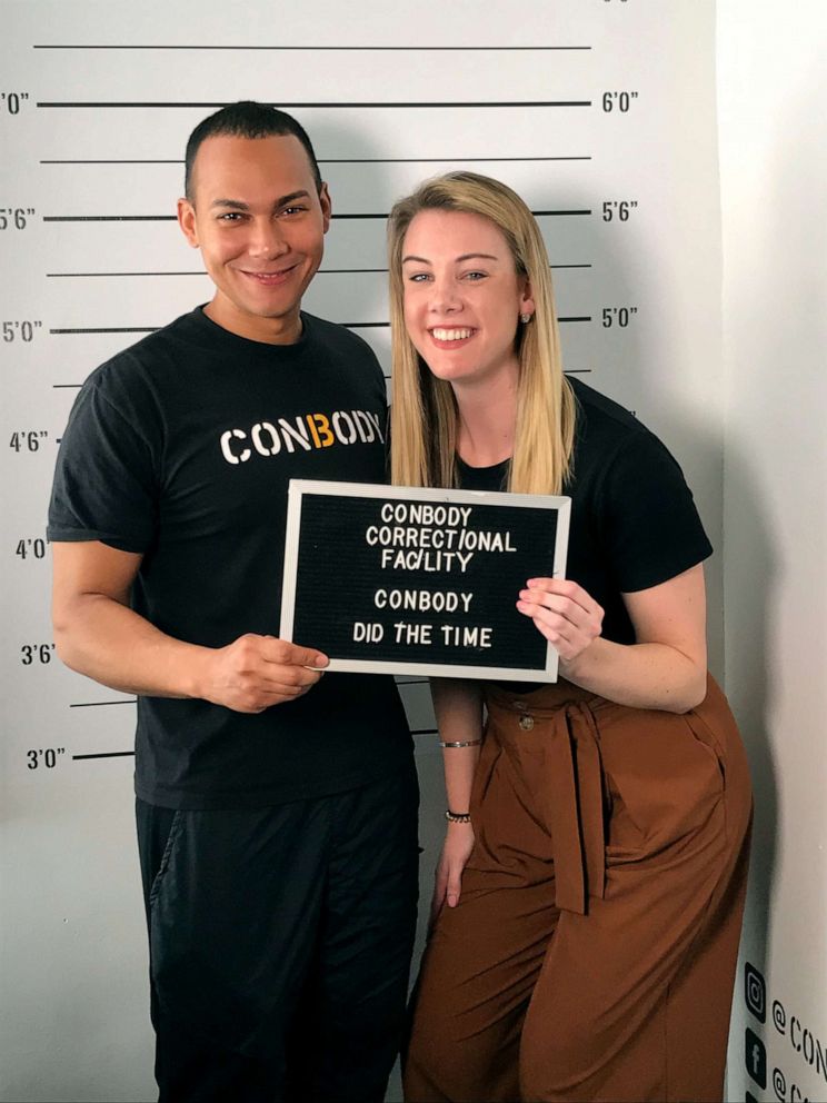 PHOTO: Shannon McLellan, right, and ConBody founder Coss Marte pose in front of the "Did the time" wall at ConBody's New York City location.