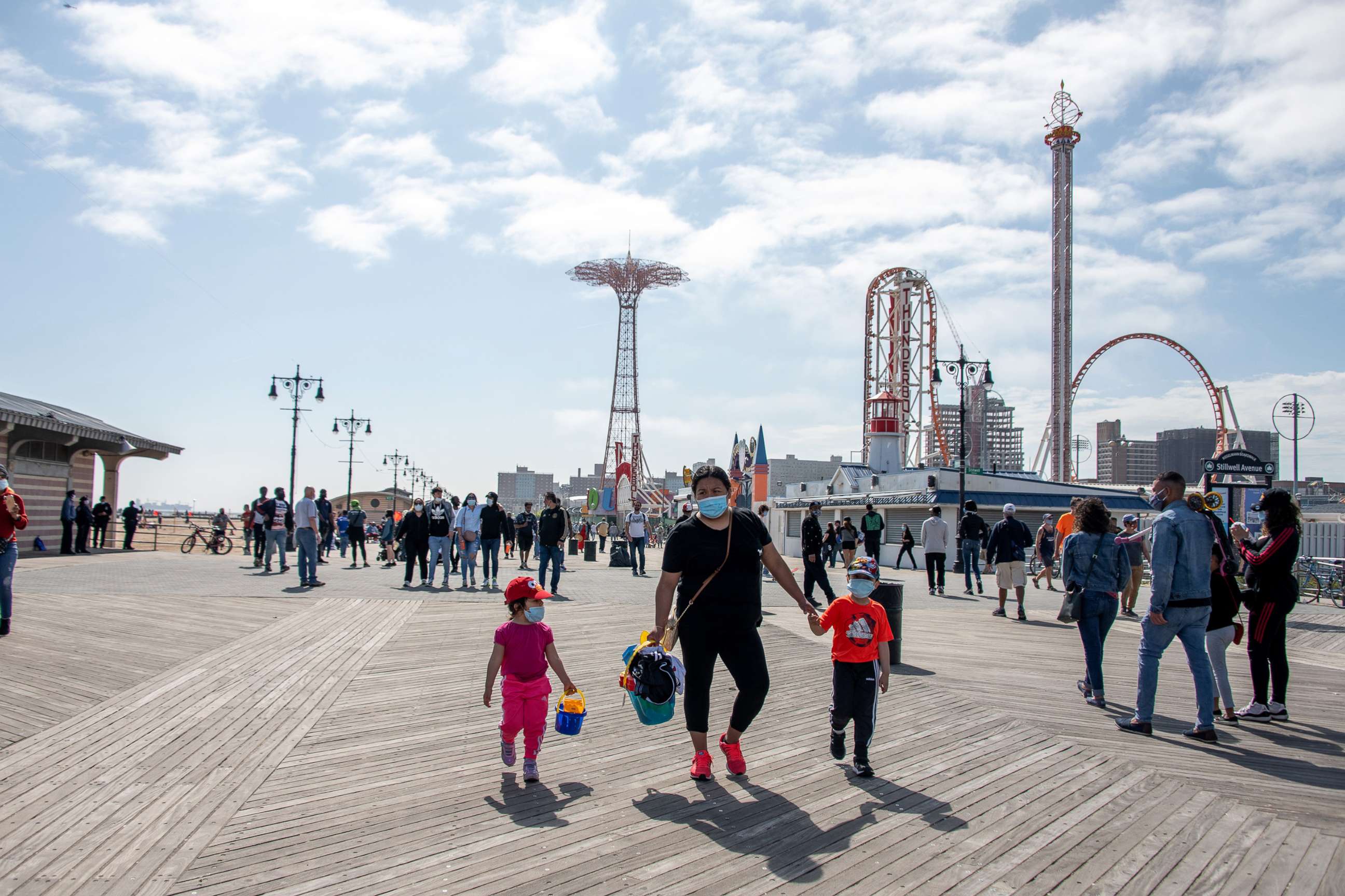 PHOTO: In this May 25, 2020, file photo, people wearing masks walk on the boardwalk at Coney Island with a view of Luna Park in the background in New York.