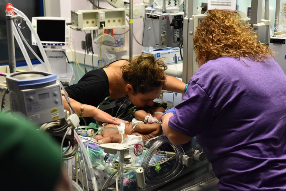 PHOTO: Amanda Arciniega kisses her infant twin daughters at Cook Children's Medical Center in Fort Worth, Texas.