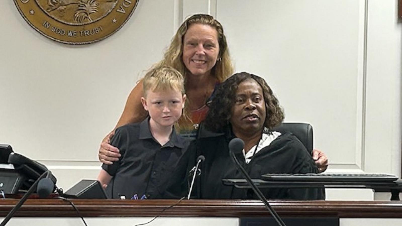 PHOTO: Jackie Coombe, center back, a former teacher, adopted her former student, Jaden, left, in June 2026.