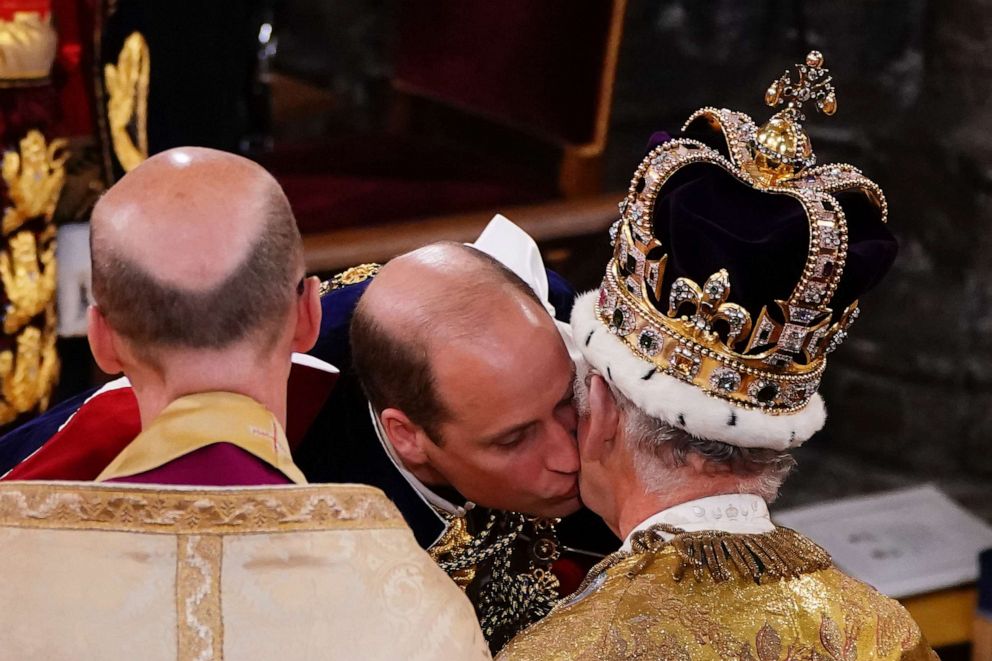 PHOTO: Prince William, Prince of Wales kisses his father, King Charles III, wearing the St Edward's Crown, during the King's coronation ceremony at Westminster Abbey, May 6, 2023, in London.